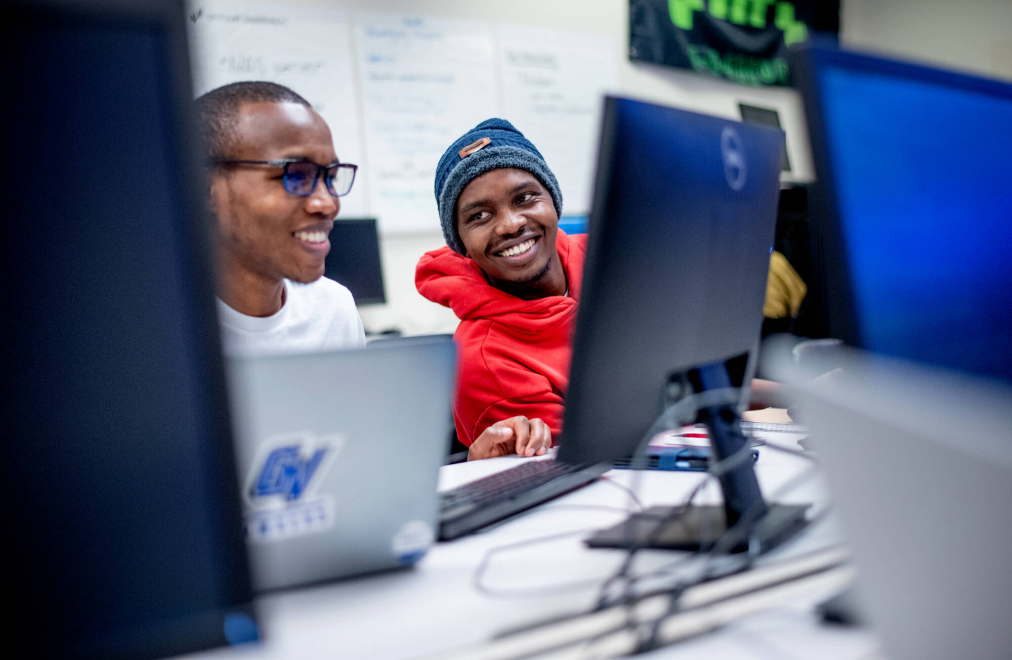 Cyber Security Range, students smile at one another and their computers